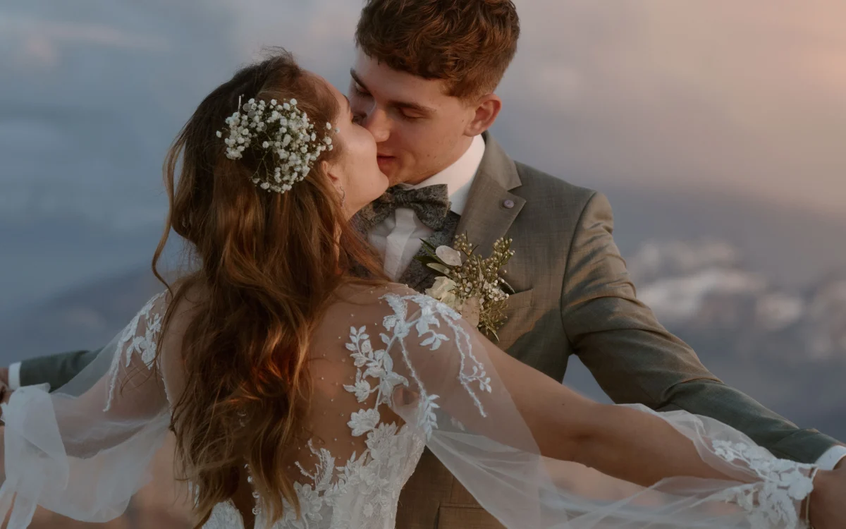 Hochzeitspaar mit ausgestreckten Armen, küssen sich vor Bergkulisse, auf dem Säntis.