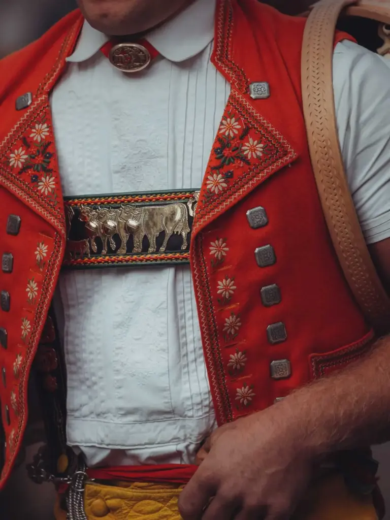 Detail of the traditional Appenzell herdsman costume: red embroidered waistcoat with edelweiss and brass fittings showing cows