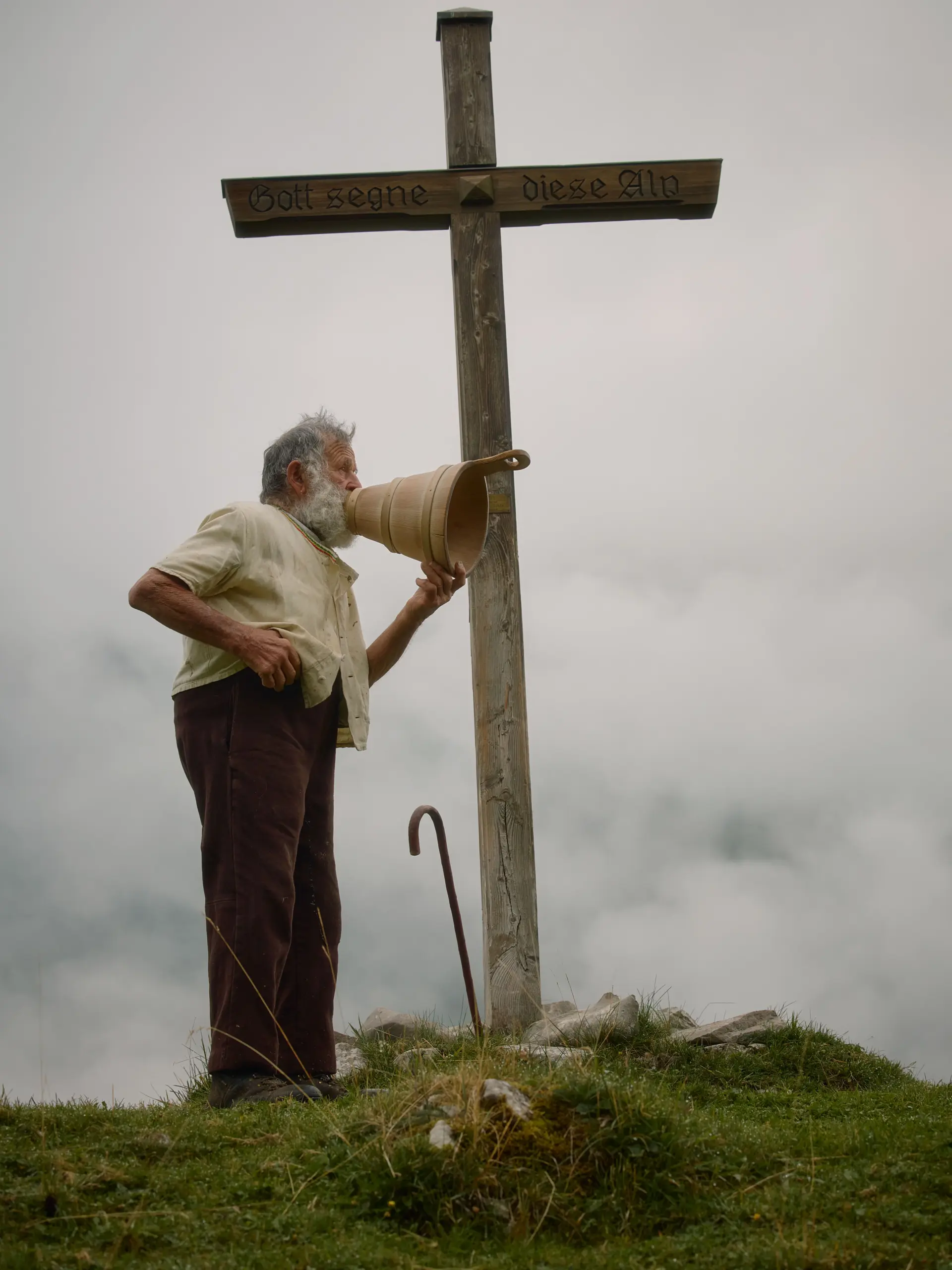 Senn gibt Alpsegen auf Berg mit Kreuz
