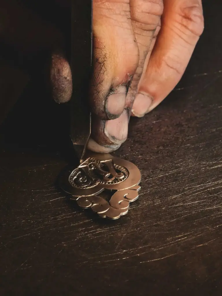 Hands chasing an ornate brass fitting, traditional Appenzell craftsmanship