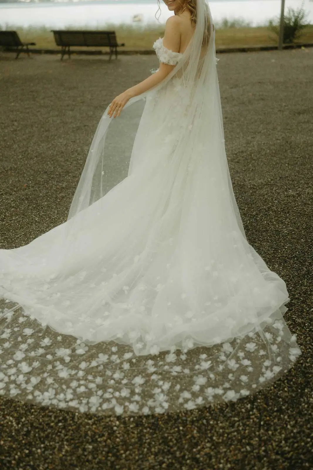 Braut im Brautkleid mit Blüten-Tüll und langer Schleppe auf dem Kiesplatz der Villa Au am Zürichsee