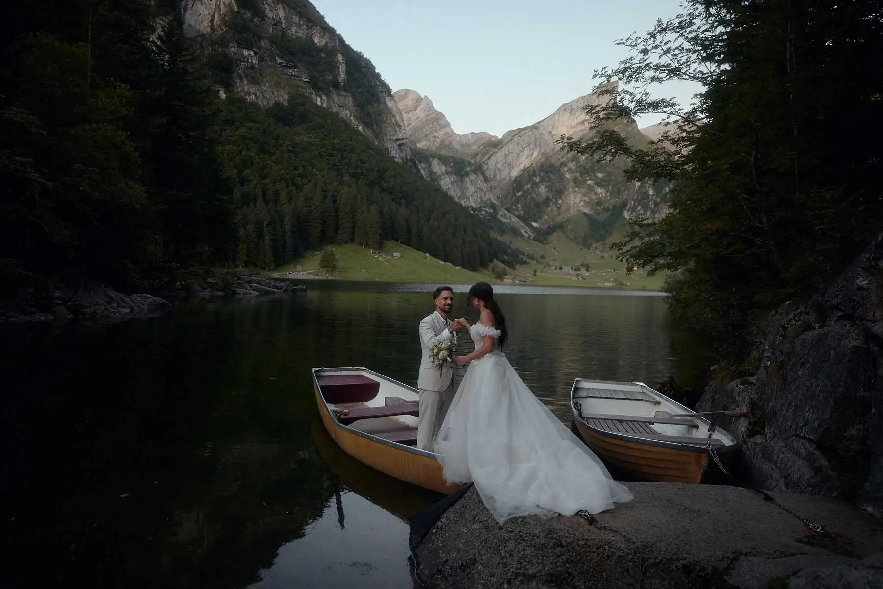 Bride and groom beside rowing boats on the shore of the Seealpsee – elopement in Appenzell, Switzerland