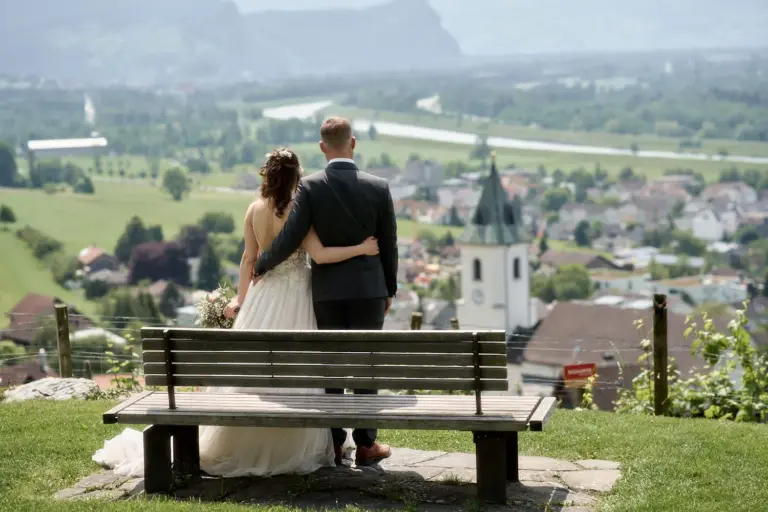 Brautpaar auf einer Bank über Triesen mit Blick ins Rheintal – Hochzeitsfotograf Liechtenstein
