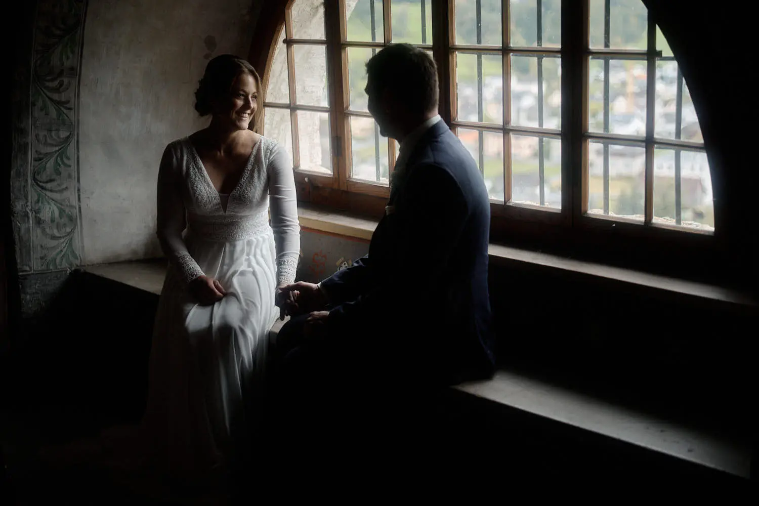 Brautpaar am Fenster eines Raums der Burg Gutenberg im Gegenlicht – Hochzeitsfotograf Liechtenstein