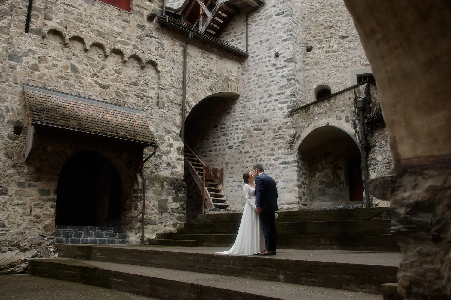 Brautpaar auf der Treppe im steinernen Burghof der Burg Gutenberg – Hochzeitsfotograf Liechtenstein