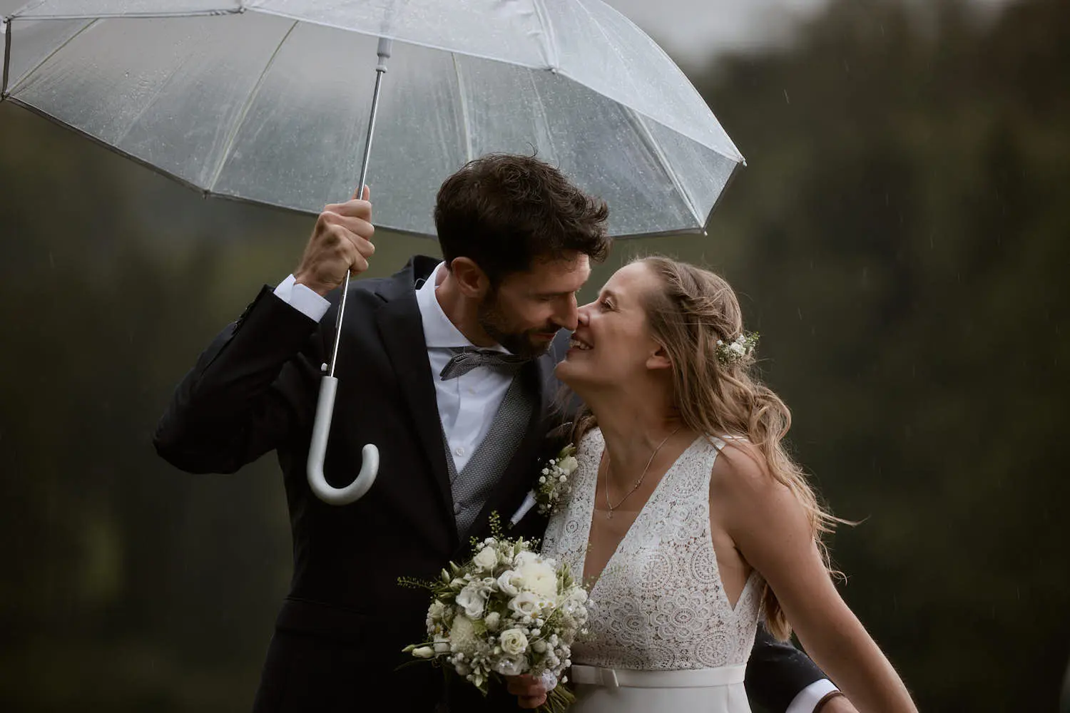 Brautpaar lacht unter einem transparenten Regenschirm, Hochzeit in Malbun – Hochzeitsfotograf Liechtenstein