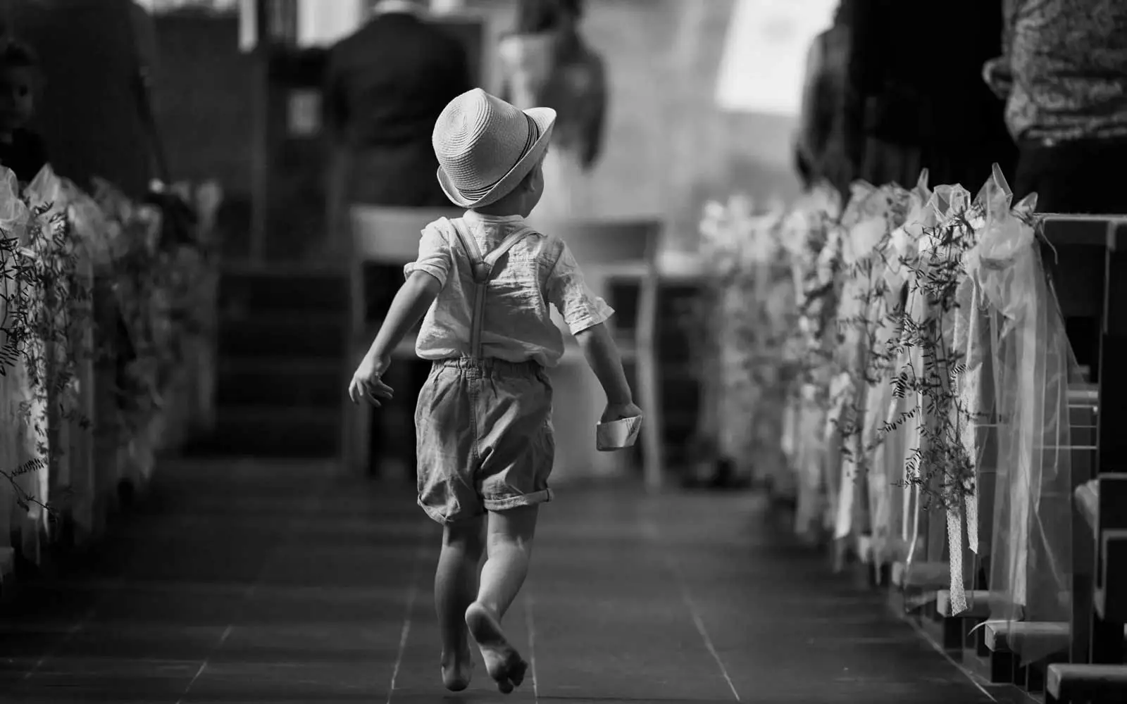 Junge in Kirche in Appenzell bei Hochzeit mit Hut auf dem Kopf von hinten fotografiert.
