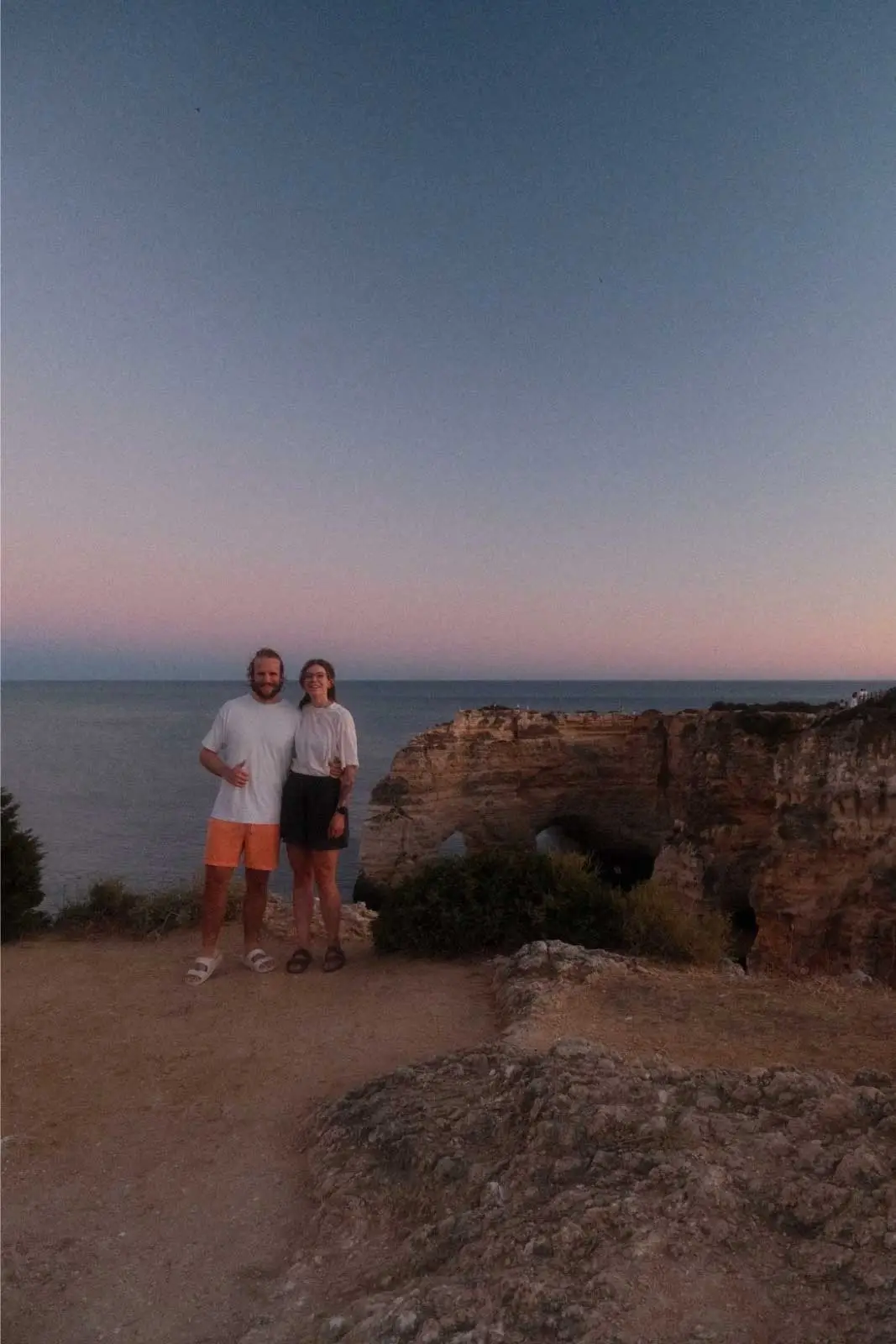 Paar auf einer Klippe über dem Meer bei Sonnenuntergang